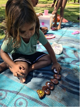 child playing with painted rocks