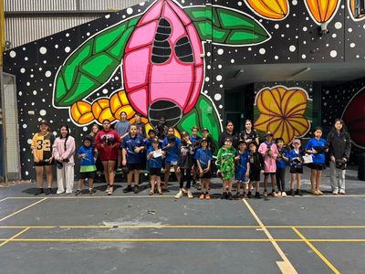 Group photo of class in front of painted wall