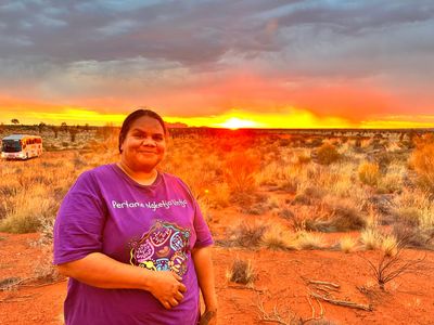 Image of woman standing in front of sunset