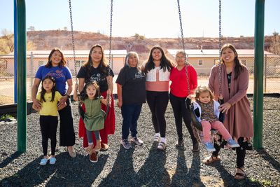 Women standing with girls at swings