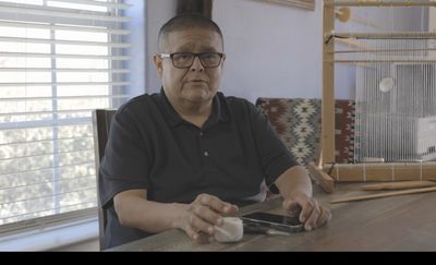 Man sitting with loom in background